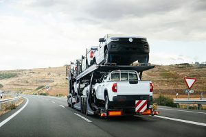 Auto carrier truck transporting multiple vehicles on open highway trailer