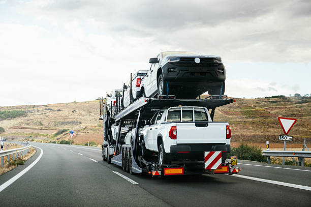 Auto carrier truck transporting multiple vehicles on open highway trailer