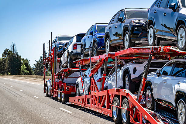 Red car carrier truck loaded with multiple vehicles traveling on highway